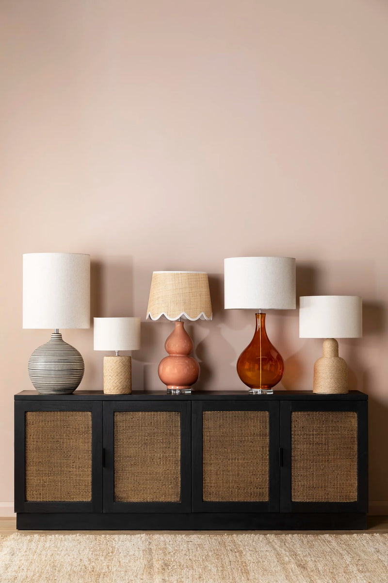Set of five lamps on a black cabinet against a beige wall