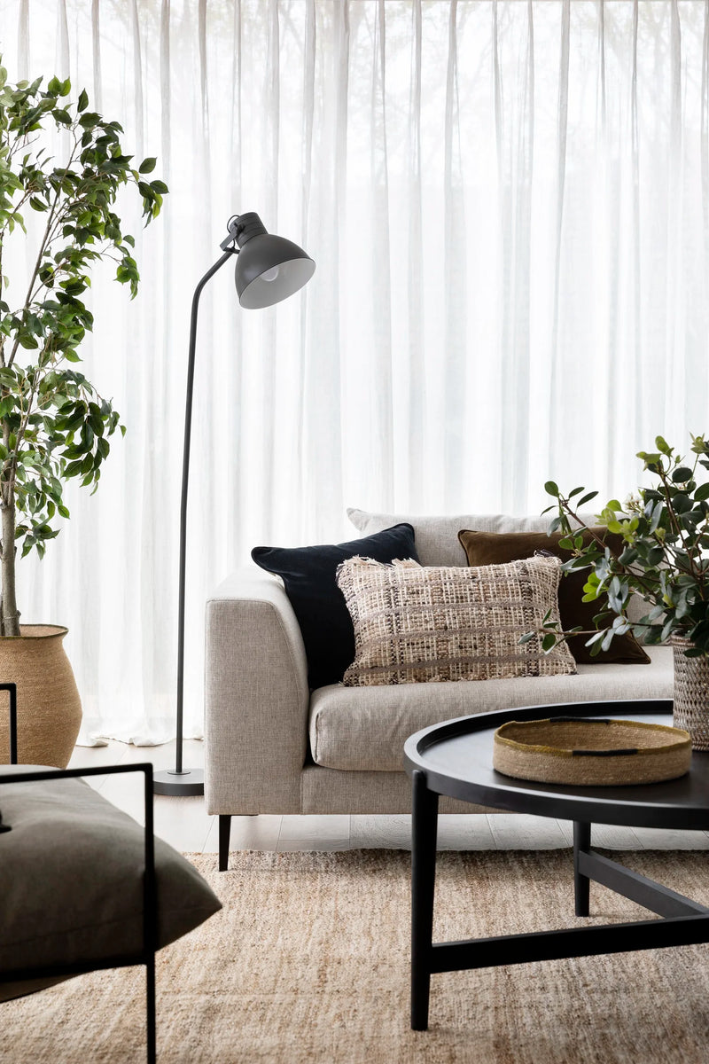 Living room with a gray sofa, black coffee table, and decorative pillows.
